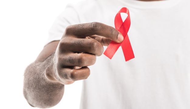 A hand holding a red ribbon for AIDS Awareness